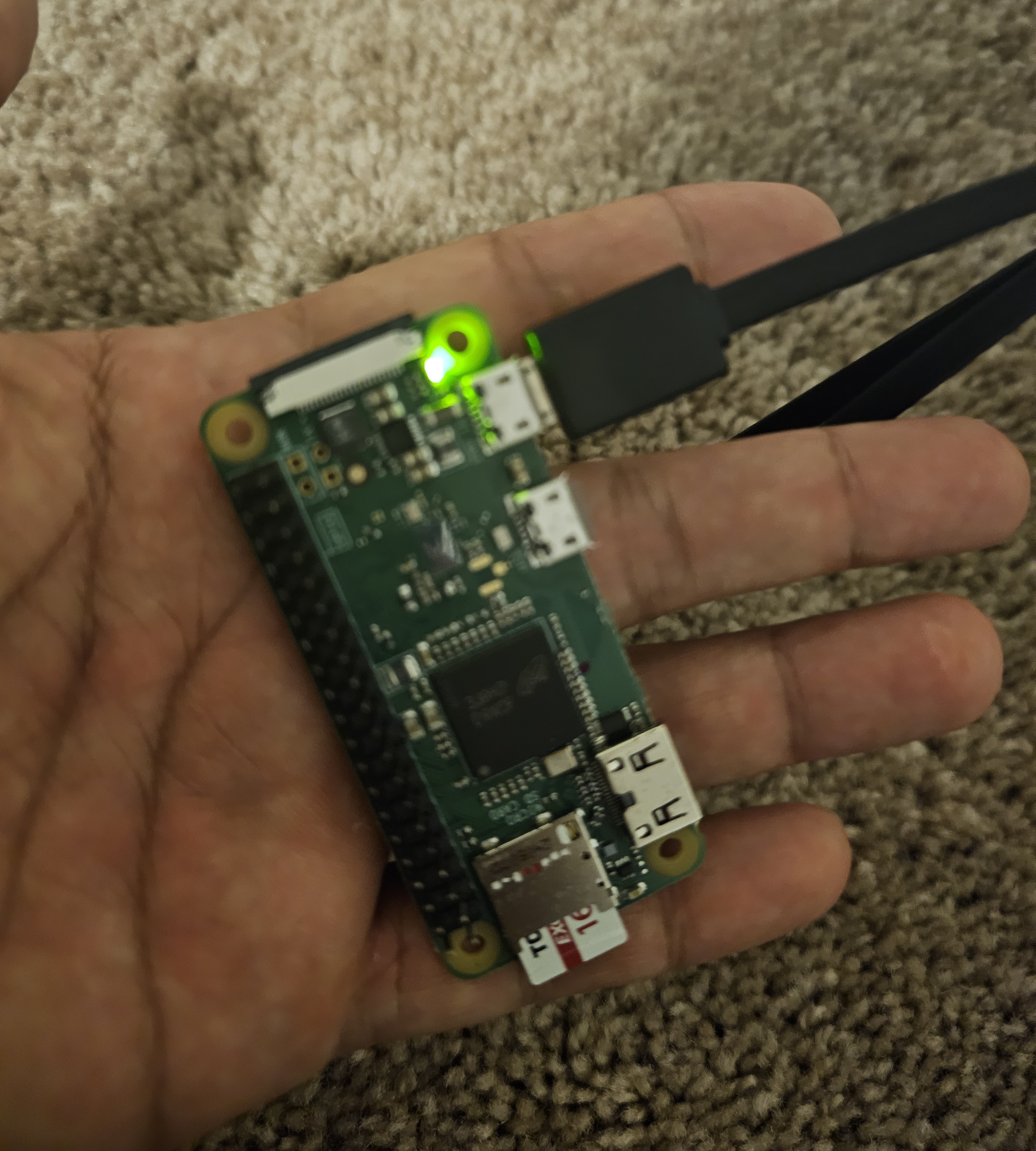 PicoClaw board powered on, green LED glowing, held in hand to show its compact size